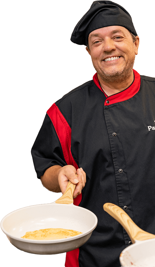 Chef David Sneed preparing fresh crepes in a sizzling pan at a live cooking event.