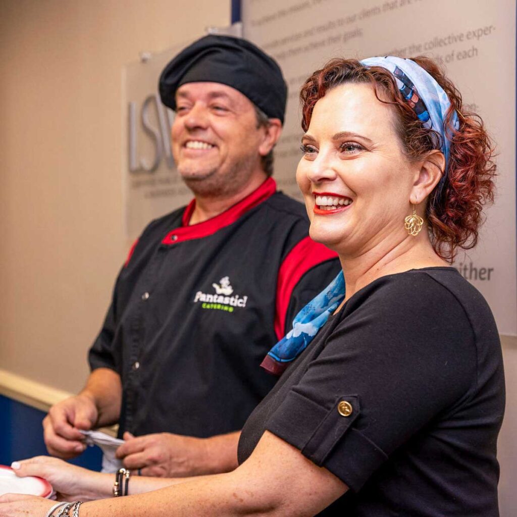 Chef David Sneed and his culinary team smiling while preparing a live-action catering service.